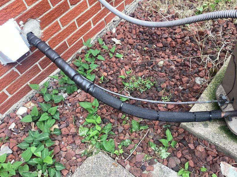 Responded to service call for exposed electrical wiring at outdoor A/C unit located at basement level. Inspected exterior condensing unit and associated electrical conduits running along building foundation through landscaped area. Properly secured and re-wrapped exposed wiring connections using appropriate electrical tape and protective conduit materials to ensure code compliance and prevent weather exposure. Verified all electrical connections were properly insulated and protected from environmental elements. Unit tested and operational upon completion.