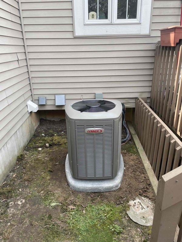 Completed installation of 2-ton Lennox air conditioning system with matching evaporator coil at residential property. Unit positioned on concrete pad in right side yard per permit specifications, with refrigerant lines and electrical conduit properly routed and connected. System tested and verified operational upon completion of reconnection procedures.