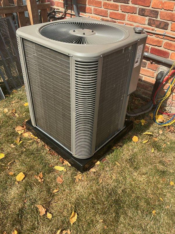 Completed routine preventative maintenance on residential air conditioning system installed in July 2022. Performed comprehensive AC tune-up including inspection of outdoor condensing unit, which was found to be operating properly with no reported issues or symptoms. Unit is positioned on proper concrete pad foundation with adequate clearance from brick wall structure. Verified all components functioning within normal parameters, cleaned condenser coils, checked refrigerant levels, inspected electrical connections, and tested system operation. All seasonal debris removed from surrounding area. System demonstrated proper airflow through louvers and fan operation. No repairs required at this time. Documented equipment condition with photographs showing unit in good working order for 2-year-old system.
