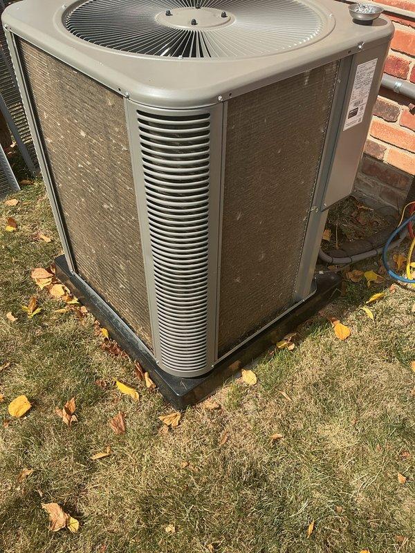 Completed routine preventative maintenance on residential air conditioning system installed in July 2022. Performed comprehensive AC tune-up including inspection of outdoor condensing unit, which was found to be operating properly with no reported issues or symptoms. Unit is positioned on proper concrete pad foundation with adequate clearance from brick wall structure. Verified all components functioning within normal parameters, cleaned condenser coils, checked refrigerant levels, inspected electrical connections, and tested system operation. All seasonal debris removed from surrounding area. System demonstrated proper airflow through louvers and fan operation. No repairs required at this time. Documented equipment condition with photographs showing unit in good working order for 2-year-old system.