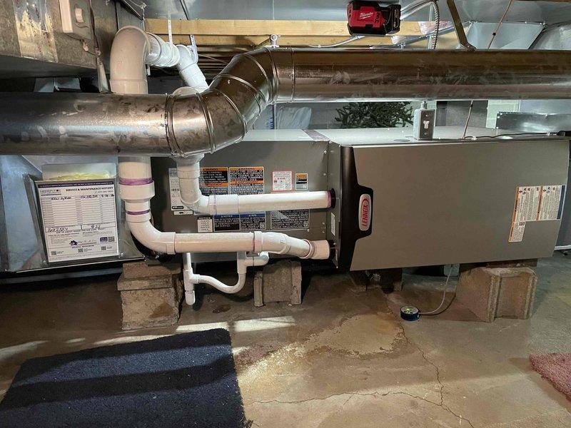 Completed full HVAC system installation in basement utility area, including horizontal 70,000 BTU furnace mounted on concrete blocks, 2.5-ton air conditioning unit with rear discharge configuration, and whole-home humidifier integration. Performed all mechanical and electrical connections per code requirements, installed PVC condensate drainage and venting systems with exterior wall penetration and proper termination through siding. Reconnected and configured all ductwork including metallic supply trunk connections, verified proper airflow distribution, tested all safety controls and limit switches, and confirmed system operation across heating and cooling modes.