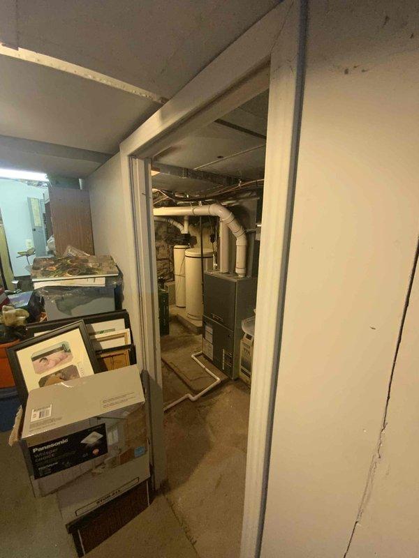 Conducted full system estimate for replacement of existing 16-20 year old furnace installation in basement utility room. Evaluated current HVAC equipment including gray metal furnace unit with associated ductwork, PVC drainage system with shutoff valve, and beige air handler with copper refrigerant lines. Customer requires immediate replacement due to age of existing equipment; air conditioning system was previously replaced in 2023.