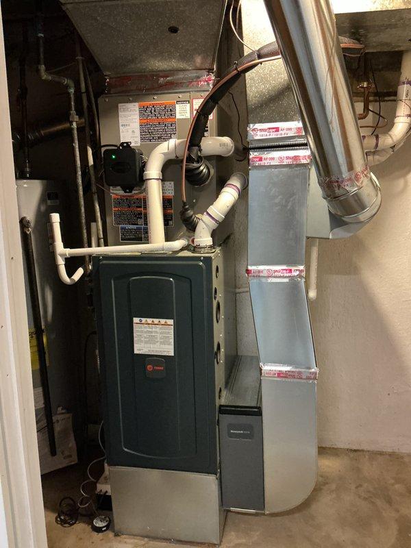 Completed full installation of 2.5-ton air conditioning system with matching evaporator coil in basement utility area. Installed new outdoor condensing unit with right-side line set configuration and connected to indoor air handler using insulated refrigerant lines. Mounted evaporator coil above existing furnace unit, installed condensate drainage system with white PVC piping routed to appropriate drain location, and completed all mechanical and electrical connections per manufacturer specifications. Verified proper refrigerant charge, tested system operation including airflow and temperature differential, and confirmed all safety controls functioning correctly. System commissioned and left in full operational status with all required permits obtained for mechanical and electrical work.
