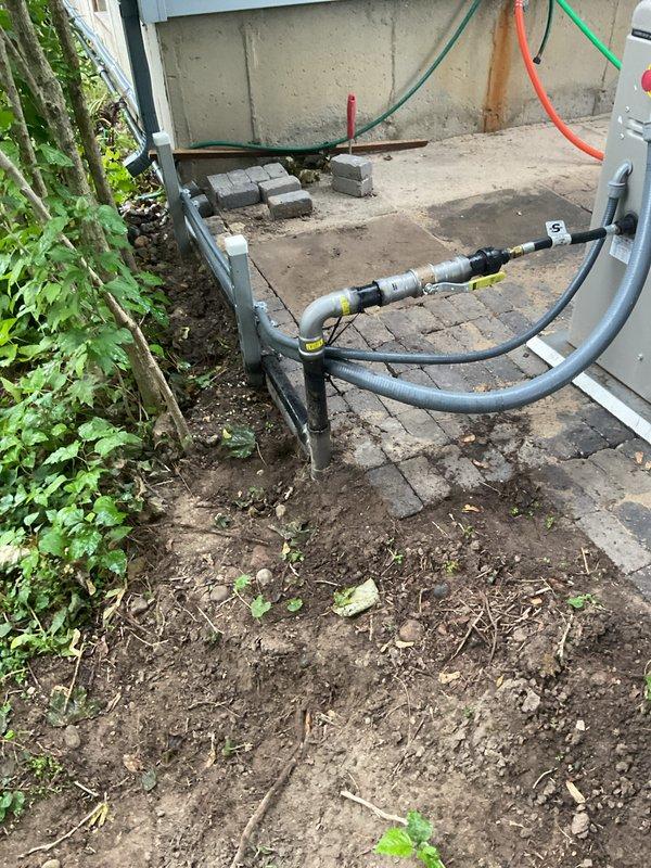 Responded to callback for ATS communication warning, not in auto warning, and date/time warning on recently installed HVAC system. Retrieved gauge and go equipment from site as scheduled. Verified outdoor unit installation and condensate drainage system properly secured with appropriate brackets and straps. Documented equipment placement and utility connections in outdoor service area adjacent to building foundation for service records.
