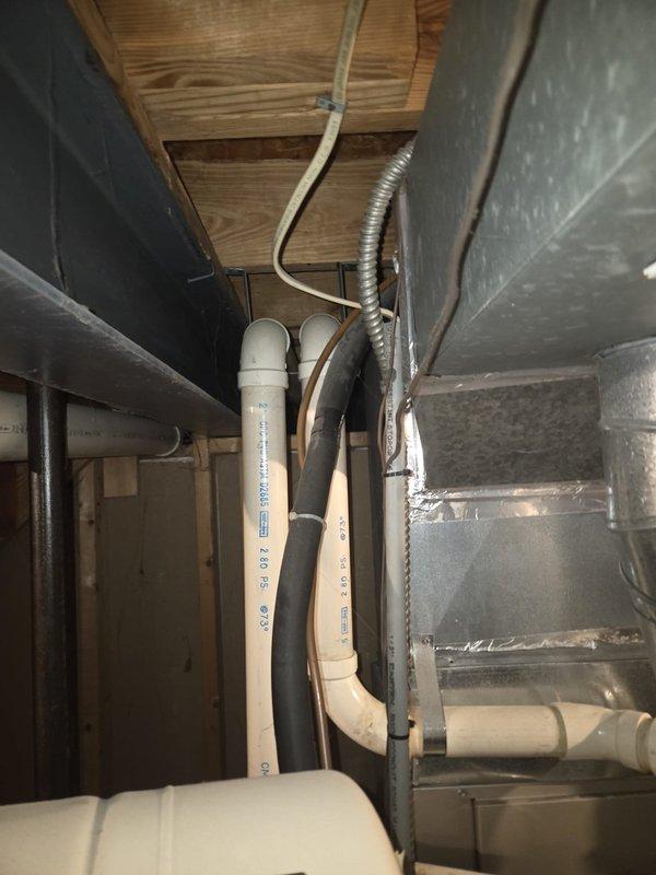 Performed comprehensive assessment of aging gas HVAC system (15+ years) including furnace unit with connected circular metal ductwork, PVC venting, and associated air handler. Evaluation included inspection of crawlspace installation conditions, examining both the main equipment and auxiliary components including ductwork integrity, condensate drainage system, and thermostat functionality. Documented current system configuration to prepare replacement recommendations for complete furnace and AC unit upgrade.