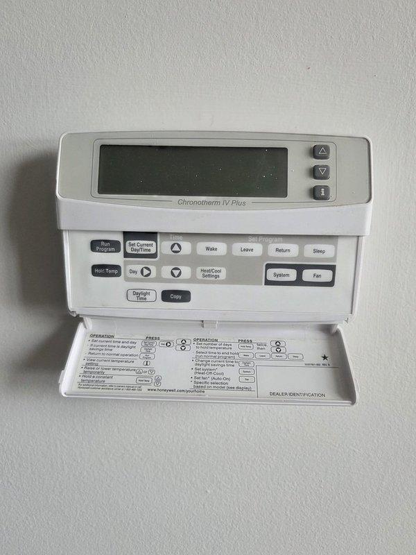 Conducted evaluation of aging HVAC system including a Honeywell Chronotherm IV Plus thermostat and basement-installed furnace unit with exposed internal components, ductwork, and PVC venting. Provided replacement estimate for complete system upgrade based on observed equipment condition and performance assessment.