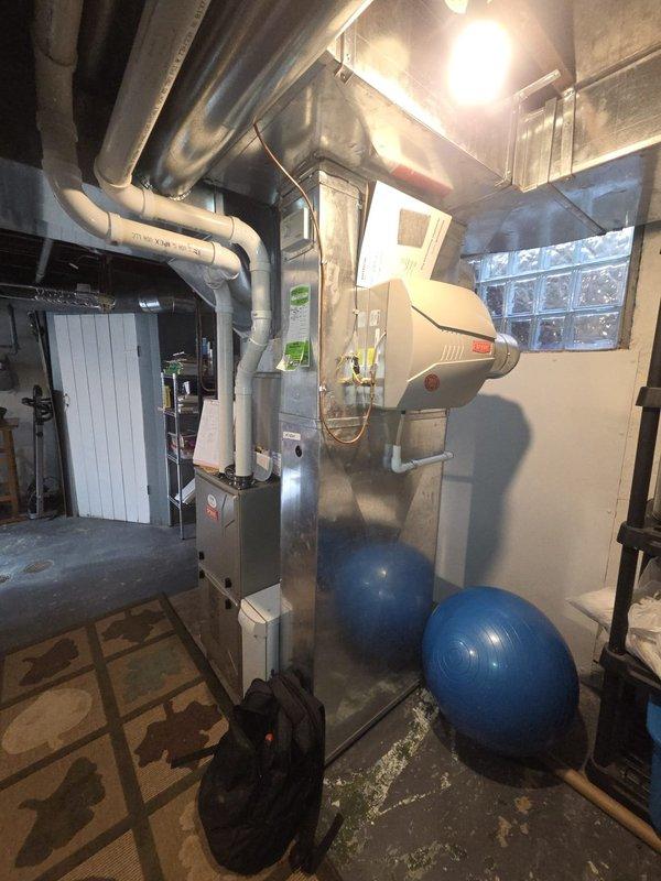 Conducted on-site assessment of existing HVAC system for replacement estimate. Documented current equipment configuration including furnace, air handler, humidifier unit, ductwork, and Honeywell programmable thermostat. Photographed mechanical room setup in basement with existing gray insulated ductwork, expansion tanks, and utility components to provide comprehensive evaluation for complete system replacement recommendations.