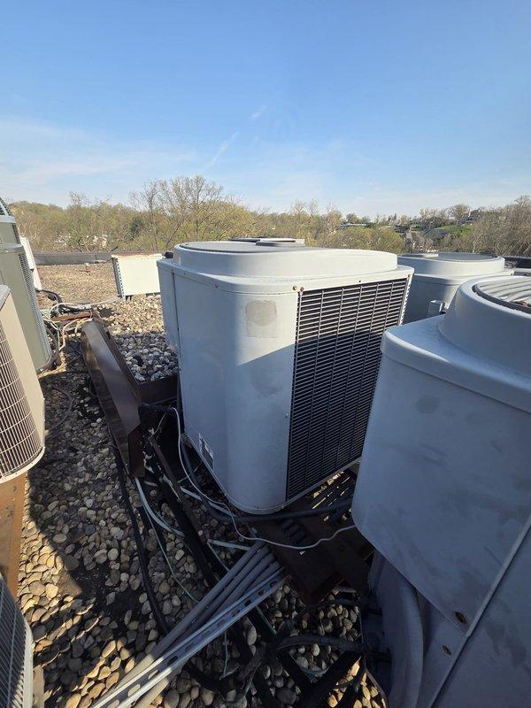 Conducted comprehensive assessment of rooftop HVAC installation featuring three R-22 heat pump systems requiring replacement due to refrigerant depletion in primary unit. Documented existing equipment configuration including multiple condensing units mounted on support frames with electrical disconnects containing aged fuses and wiring. Determined crane access will be necessary for removal and installation of rooftop units given building height and equipment positioning on gravel-surfaced roof.