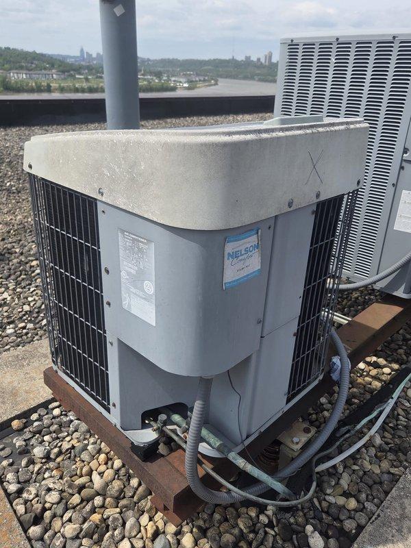 Provided comprehensive estimate for rooftop air conditioning system replacement. Evaluated existing gray condenser unit mounted on gravel ballast roof, assessed condition of equipment, support platform, electrical connections, and refrigerant lines. Documented current system specifications and return air grille configuration to determine proper replacement unit sizing and compatibility requirements.