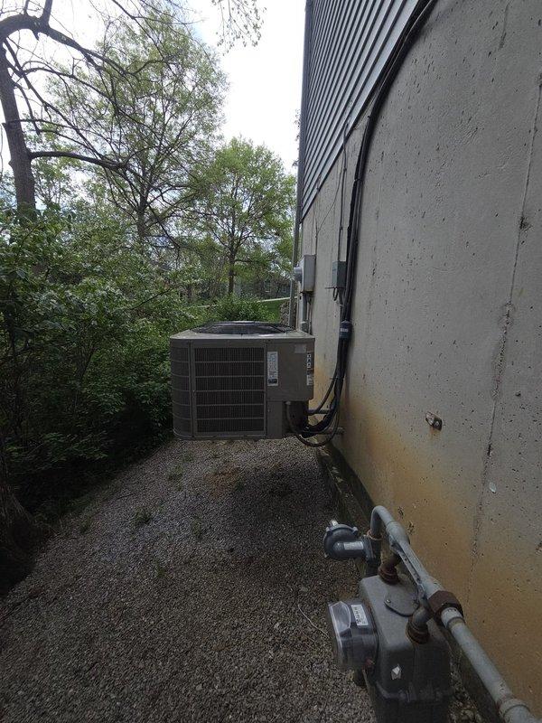 Conducted on-site estimate for gas forced air furnace replacement system located in basement. Evaluated existing HVAC equipment including dual thermostat configuration with programmable digital and basic analog units mounted on interior wall. Assessed exterior air conditioning condenser unit positioned on gravel pad with associated electrical conduit and connections. Documented current system specifications, equipment placement, and utility connections including gas meter location. Provided comprehensive replacement options and recommendations for new furnace installation.