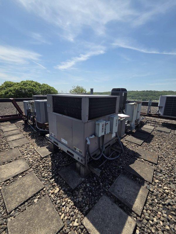 Completed rooftop unit replacement and exercise room HVAC system installation at commercial facility. Removed existing equipment and installed new packaged rooftop air handling unit with proper electrical conduit connections and refrigerant line routing. Verified proper clearances and mounting on ballasted paver roof system, ensuring adequate spacing between equipment and building components as documented with field measurements.