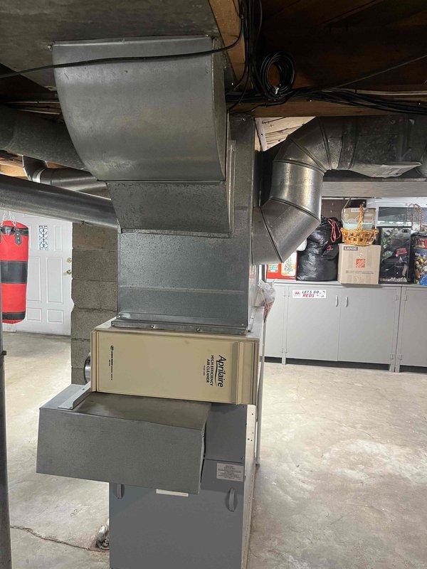 Conducted comprehensive assessment of existing residential HVAC system located in basement utility area for equipment replacement estimate. Evaluated current Nordyne furnace unit with connected galvanized metal plenum and ductwork distribution system. Inspected existing metallic ductwork network including cylindrical trunk lines, supply branches, and elbow configurations throughout the space. Documented equipment specifications, spatial constraints, and structural considerations including support column placement and ceiling joist clearances. Photographed current system configuration to provide detailed replacement recommendations and equipment sizing requirements.