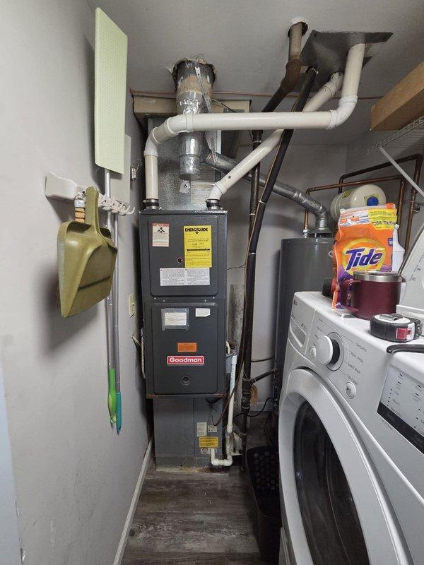 Conducted comprehensive evaluation of existing HVAC system including Goodman furnace unit and thermostat controls located in utility room. Documented current equipment configuration, wiring connections at thermostat terminal board (W, RH, R, RC terminals with corresponding colored wires), and PVC condensate drainage routing. Assessed system for replacement options and provided estimate for new air conditioning equipment installation.