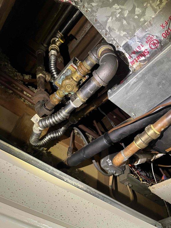 Conducted commercial air conditioning replacement estimate and documented existing mechanical infrastructure. Inspected gas valve assembly, piping connections, and associated HVAC components in utility space, photographing brass valve fittings, flexible gas connectors, copper distribution lines, and equipment mounting configuration to provide accurate replacement specifications.