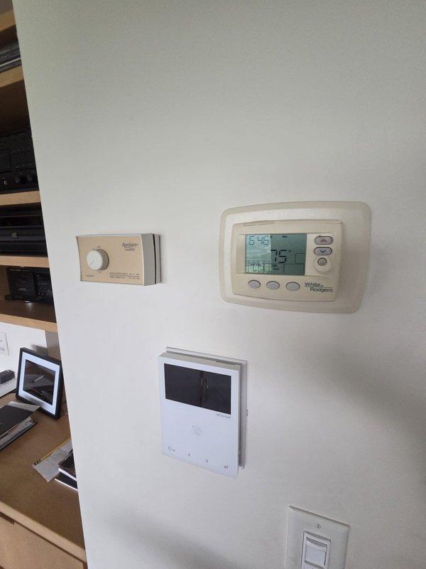 Conducted comprehensive site assessment for HVAC system replacement at residential property. Evaluated existing rooftop equipment including multiple condensing units and air handlers, noting unit marked for replacement. Documented current indoor control system configuration including Aprilaire humidistat and White-Rodgers digital thermostat displaying operational temperatures. Assessed refrigerant line routing, electrical conduit connections, and equipment accessibility on gravel-surfaced roof. Provided replacement estimate for aging HVAC equipment based on system evaluation and performance requirements.