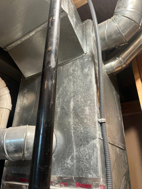 Conducted comprehensive assessment of existing HVAC system for complete replacement estimate. Evaluated attic-installed ductwork system, noting substantial dust accumulation on galvanized metal ducts and components requiring consideration for replacement or cleaning during system upgrade. Documented current duct configuration including rectangular trunk lines, cylindrical branch ducts, flexible conduit connections, and PVC condensate drainage piping. Assessed accessibility via interior staircase to lower level for equipment placement options. Photographed existing installation conditions to support equipment sizing recommendations and scope of work development for complete system replacement proposal.
