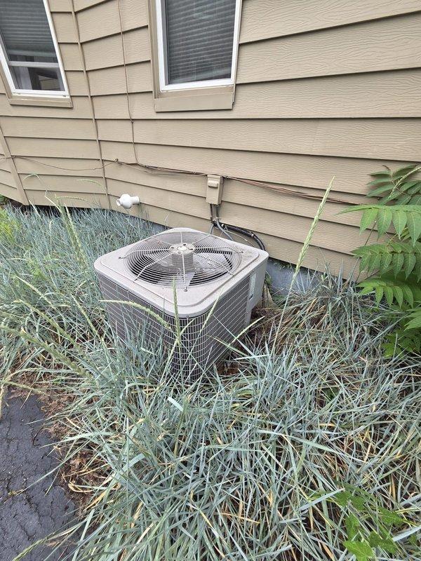 Conducted comprehensive estimate for complete air conditioning system replacement following previous service call that identified low refrigerant levels. Evaluated existing outdoor condenser unit and indoor air handler system, documented current equipment condition including overgrown vegetation obstructing condenser airflow, and assessed ductwork configuration in basement utility area. Provided replacement options and recommendations to address system deficiencies.