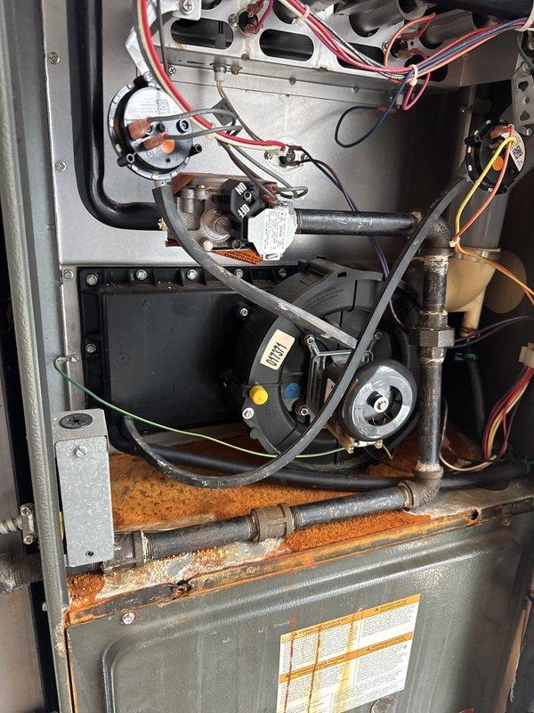 Responded to no cooling complaint at commercial facility. Upon inspection, discovered outdoor condenser unit with associated electrical disconnect and indoor HVAC components including circulation pump system. Documented extensive rust and corrosion on interior metal panels and piping, indicating prolonged moisture exposure that could compromise system integrity and performance. Photographed equipment condition for maintenance records.