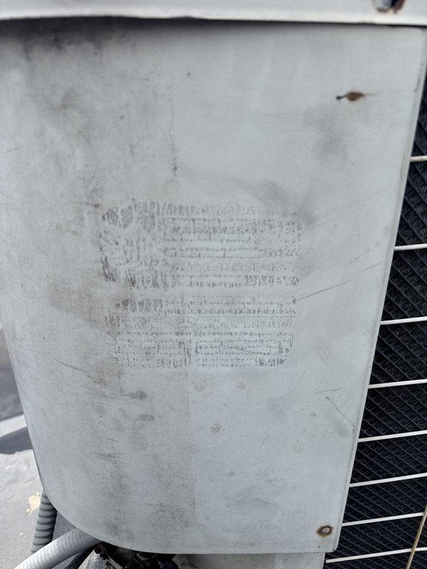 Responded to service call for commercial rooftop A/C unit not cooling at vacant property. Upon arrival, performed diagnostic evaluation of packaged rooftop unit showing signs of weathering and age. Inspected condenser unit exterior panels, coil condition, and refrigerant line set with insulation. Checked electrical disconnect and verified power supply to unit. Assessed standing water on roof membrane surrounding equipment, noting potential drainage concerns. Documented unit condition including weathered housing, discolored exterior panels, and exposed condenser coil fins. Unit required further diagnostics to determine root cause of cooling deficiency in refrigerant lines.
