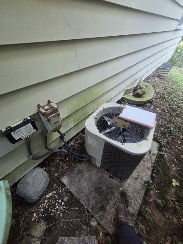 Conducted on-site evaluation of existing air conditioning system for replacement estimate. Inspected two outdoor condenser units mounted on concrete pad showing signs of age and weathering, documented electrical service panel configuration, and assessed current HVAC infrastructure to provide comprehensive replacement options and recommendations.