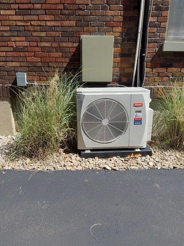 Completed installation of Bryant ductless mini-split system consisting of one 37MGHAQ18CA3 1.5-ton outdoor condensing unit and two D5MAHAQ09XA3 high-wall indoor air handlers. Installed new equipment pad for outdoor unit, ran electrical whip to unit, and mounted disconnect box with fuses on exterior brick wall. Flushed and reused existing line sets to connect indoor units to outdoor condenser. Mounted one indoor unit in bathroom near ceiling and positioned outdoor unit on pad with landscaping. System tested and operational with 10-year parts and labor warranty coverage.