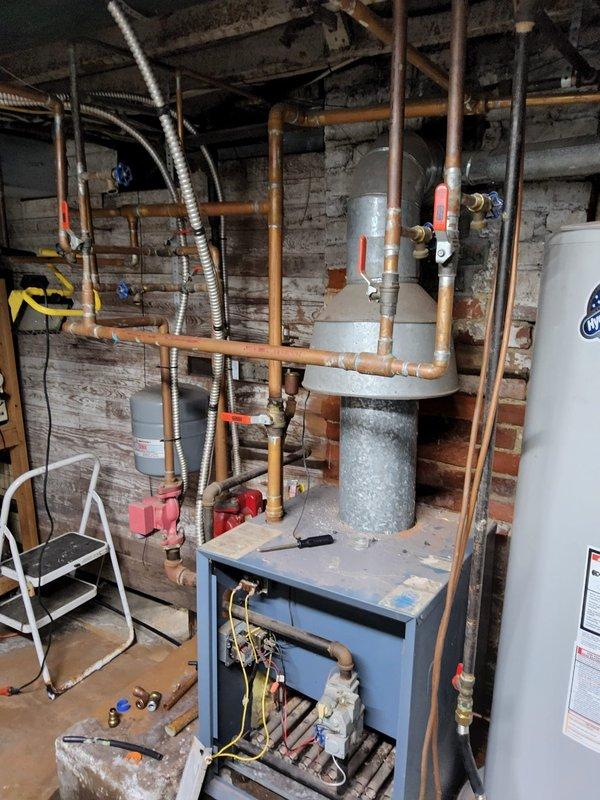 Conducted estimate for boiler replacement in basement mechanical room. Assessed existing system including blue-gray boiler unit, Grundfos UPS 15-42 F circulation pump (115V, 1PH, 60 Hz), copper piping network with shutoff valves, galvanized expansion tank, and associated hydronic heating components. Documented current equipment condition and photographed installation for replacement specifications.