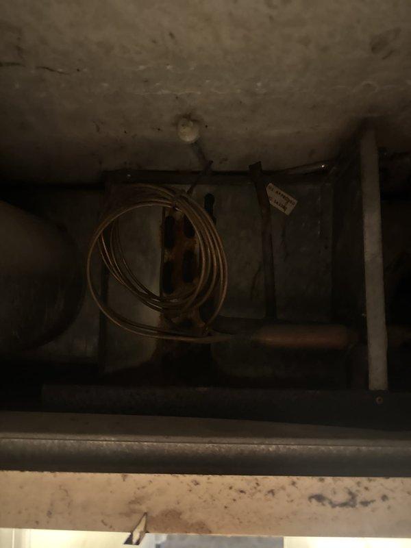 Responded to no cooling complaint at commercial property. Upon arrival, accessed unit and inspected mechanical compartment and internal components. Found signs of age and wear throughout system including staining on interior surfaces and dust accumulation. Examined electrical controls, relays, and wiring connections within compartment. Documented unit condition with photos showing copper refrigerant lines, control module, and electrical components for service records.