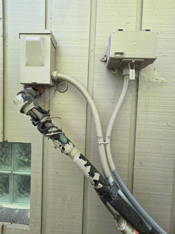 Conducted comprehensive site assessment for geothermal system installation at residential property. Existing outdoor heat pump unit exhibits severe environmental deterioration with extensive mold, mildew, and organic growth on metal casing, indicating end of service life and need for replacement. Documented damaged exterior refrigerant line insulation with torn jacketing and exposed degraded material requiring immediate replacement. Evaluated electrical components, conduit routing, and wall penetrations for geothermal system integration. Photographed existing equipment condition and installation area to develop accurate proposal for geothermal heat pump system replacement.