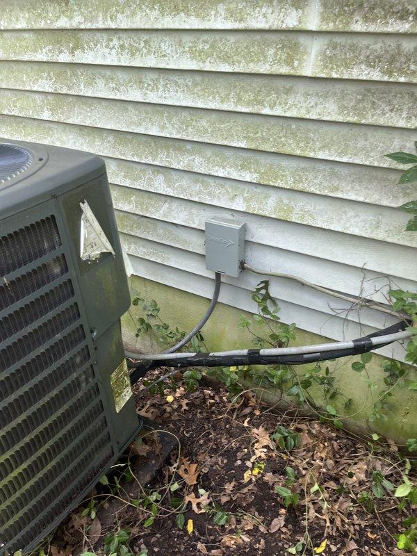 Conducted comprehensive assessment of two outdoor air conditioning condenser units for replacement estimate. Both units showed significant age-related deterioration with weathered casings, discoloration, and grime accumulation. Documented existing equipment conditions including unit positioning on concrete pads, electrical disconnect boxes, refrigerant line routing, and conduit installations. Noted substantial environmental factors affecting equipment including algae growth on building siding, vegetation encroachment around unit bases, and inadequate clearance maintenance that could impact future system performance and serviceability.
