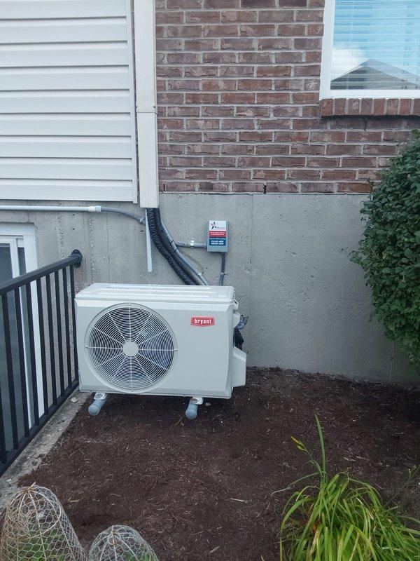 Completed full installation of Bryant single-zone ductless mini-split system consisting of model D5MAHAQ12XA3 indoor high-wall unit and model 37MAHAQ12AA3 outdoor condenser unit. Mounted outdoor condenser on foundation pad at exterior wall with proper clearances, installed electrical disconnect box on foundation wall, and ran black electrical conduit from unit to disconnect. Installed indoor air handler in upper corner of interior room with proper positioning for optimal air distribution. Ran refrigerant line set and electrical connections between indoor and outdoor units through exterior wall penetration. Completed all electrical connections, vacuum and pressure tested refrigerant lines, charged system to manufacturer specifications, and verified proper operation of all system functions including cooling performance and airflow.