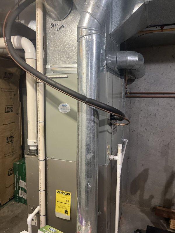 Conducted comprehensive HVAC system assessment for complete furnace and air handler replacement in residential basement utility space. Documented existing beige-colored furnace unit with associated galvanized sheet metal ductwork, flexible duct connections, PVC condensate drainage lines, and copper refrigerant piping. Photographed current system configuration including vertical and horizontal duct runs, exposed pink fiberglass insulation in wall cavities, and concrete block wall mounting location. Evaluated existing ENERGYSOURCE labeled unit for replacement specifications and measured clearances for new equipment installation. Provided detailed estimate for complete system replacement including removal of existing furnace, installation of new high-efficiency unit, ductwork modifications as needed, and proper connection of all utilities and drainage systems.