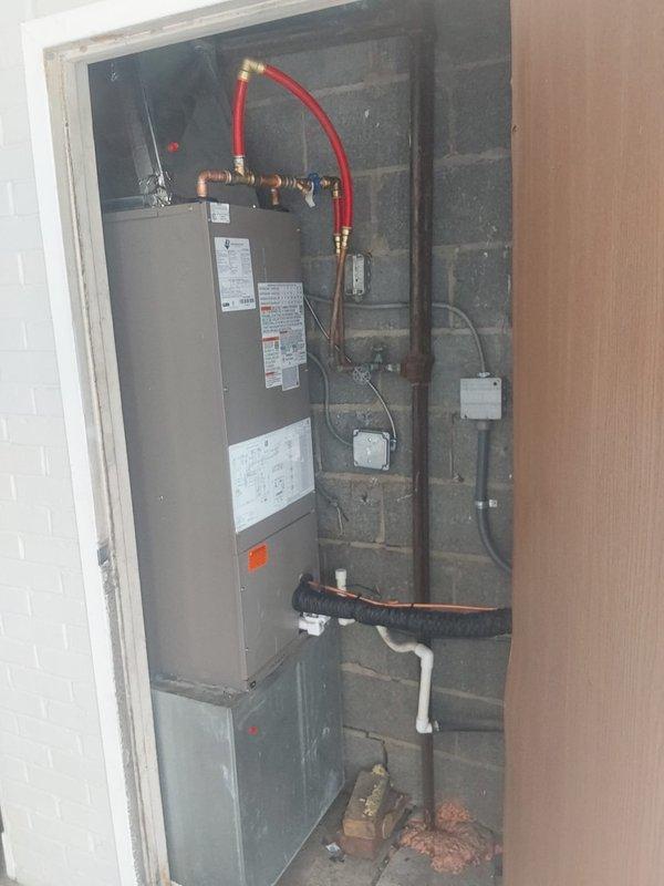 Completed full HVAC system installation including Bryant GA4SAN524 air conditioning unit relocated to ground level on rubber pad with gravel base, and BCRVMA2124S314 water fan coil unit installed in interior mechanical closet. Connected all refrigerant lines, installed new copper piping and fittings to existing water supply with brass valves and flexible connections, ran electrical conduit and wiring from exterior disconnect panel to condensing unit, completed all PVC and corrugated drain line connections, installed new programmable thermostat, pulled permit, and verified system operation with proper airflow and temperature differential.