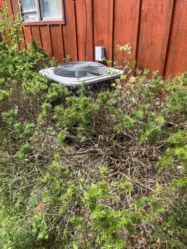 Conducted on-site evaluation of residential air conditioning system for replacement estimate. Assessed existing outdoor condensing unit located against perimeter fence, noting equipment accessibility concerns due to significant vegetation overgrowth surrounding unit. Documented current system condition through photographic survey, capturing condenser placement, clearance restrictions, and environmental factors affecting equipment performance and serviceability. Recommended vegetation clearance to meet manufacturer specifications for proper airflow and future maintenance access.