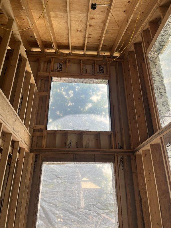 Conducted on-site assessment for air conditioning and gas furnace replacement in residential property currently under construction. Evaluated existing framing structure, reviewed architectural floor plans showing living spaces with varying ceiling heights, and documented installation requirements. Photographed construction site conditions including window openings, electrical routing, and spatial layout to determine optimal equipment placement and ductwork configuration for the new HVAC system.