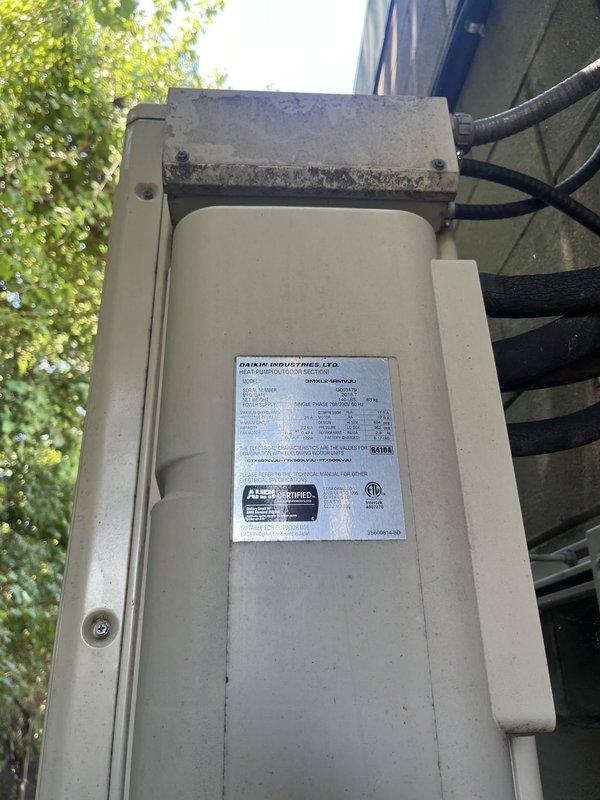Conducted commercial estimate for complete mini-split system replacement. Existing Daikin outdoor condenser unit mounted on exterior concrete block wall was evaluated and determined to be non-operational. Documented current installation including wall-mounted condensing unit with protective overhead cover, refrigerant line connections, electrical disconnect box, and associated conduit routing for replacement specifications.