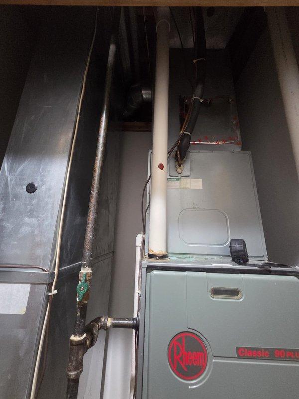 Conducted comprehensive assessment of existing residential HVAC system for complete replacement. Evaluated current equipment configuration including furnace, air handler, refrigerant lines, condensate drainage, and associated ductwork in basement utility space. Documented existing Classic 90 Plus furnace installation, copper refrigerant line routing with shutoff valves, PVC venting system, humidifier unit, gas piping connections, and electrical wiring configuration. Photographed equipment layout and spatial constraints to determine optimal replacement specifications and equipment sizing requirements for new system installation.