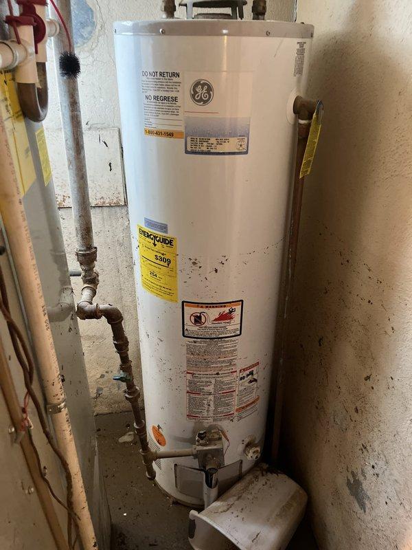Conducted on-site assessment of flooded HVAC system in residential utility room. Inspected furnace unit with front panel removed, exposing blower motor, internal wiring, and mechanical components affected by water damage. Evaluated condition of beige metal cabinet furnace with PVC exhaust/intake venting, associated ductwork, and electrical connections. Assessed water heater positioned adjacent to heating system for potential impact from flooding incident. Documented extensive water damage to concrete floor area and equipment. Prepared comprehensive replacement estimate for complete HVAC system replacement due to flood damage rendering existing equipment non-serviceable.