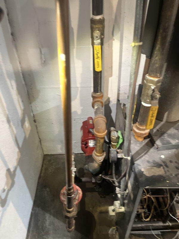 Conducted comprehensive assessment of residential boiler heating system showing visible signs of deterioration. Documented extensive corrosion, water damage, and mineral deposits on lower front panel of boiler unit, indicating potential leak or condensation issues requiring attention. Evaluated existing piping configuration including copper supply lines, gate valves, and connection points throughout the system. Photographed current condition of equipment and plumbing assembly for estimate preparation and recommended replacement or repair options based on observed wear patterns and system age.