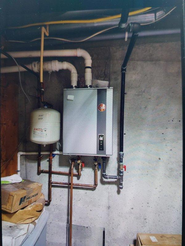 Returned to property for follow-up inspection of previously installed tankless water heater system in basement utility area. Verified proper operation of wall-mounted unit with copper supply lines and hot/cold isolation valves, confirmed expansion tank installation and mounting stability, and inspected PVC venting connections. Additionally examined HVAC system components including refrigerant line insulation, condensate drainage piping, and verified all plumbing and mechanical connections were secure with no active leaks detected.