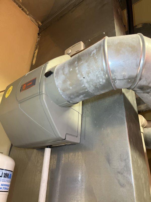 Conducted comprehensive assessment of existing HVAC system in basement utility area for complete equipment replacement. Evaluated current furnace/air handler unit, ductwork infrastructure, and associated condensate drainage system including multiple PVC pipe runs and fittings. Documented equipment condition showing dust accumulation and normal wear, photographed existing installation layout including galvanized metal ductwork, electrical connections, and ventilation components to provide accurate replacement estimate and system specifications.