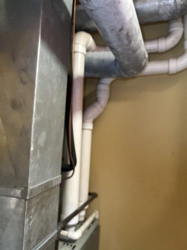 Conducted comprehensive assessment of existing HVAC system in basement utility area for complete equipment replacement. Evaluated current furnace/air handler unit, ductwork infrastructure, and associated condensate drainage system including multiple PVC pipe runs and fittings. Documented equipment condition showing dust accumulation and normal wear, photographed existing installation layout including galvanized metal ductwork, electrical connections, and ventilation components to provide accurate replacement estimate and system specifications.