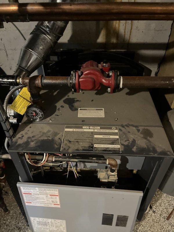 Provided estimate for complete boiler replacement after system failure due to flooding. Evaluated existing Weil-McLain boiler unit with associated piping, valves, and ductwork connections that sustained water damage and is no longer operational. Documented current equipment configuration including copper piping, red isolation valves, and mechanical connections to prepare comprehensive replacement proposal.