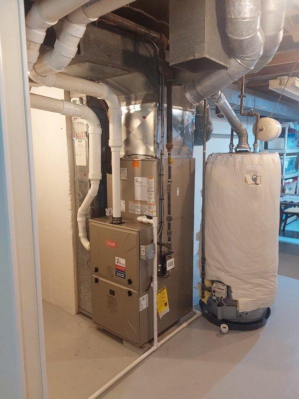 Completed full HVAC system replacement including installation of Bryant 927TA60080V21 Preferred series gas furnace, Bryant 148TAN 3-ton two-stage air conditioner utilizing R454B refrigerant, and CVAVA3621XMA cased vertical V-coil evaporator coil in basement mechanical room. Installed Honeywell T6 Pro programmable thermostat for system control, set new concrete pad for outdoor condensing unit positioned against exterior foundation wall, and ran new electrical whip with disconnect and fuse protection to outdoor unit. Cleaned and reused existing refrigerant line sets, connected all ductwork to new furnace, and verified proper drainage for condensate system with PVC piping routed to appropriate drain location.