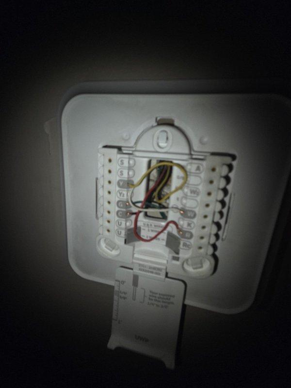 Performed comprehensive HVAC system evaluation for potential replacement. Inspected existing furnace and air conditioning equipment in basement mechanical room, documenting current thermostat wiring configuration and overall system condition. Assessed gray furnace unit with associated PVC venting, air handler components, copper refrigerant lines, and ductwork installation. Photographed thermostat terminal connections showing multi-wire setup and equipment layout to provide detailed replacement estimate recommendations.