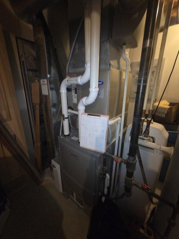 Performed comprehensive HVAC system evaluation for potential replacement. Inspected existing furnace and air conditioning equipment in basement mechanical room, documenting current thermostat wiring configuration and overall system condition. Assessed gray furnace unit with associated PVC venting, air handler components, copper refrigerant lines, and ductwork installation. Photographed thermostat terminal connections showing multi-wire setup and equipment layout to provide detailed replacement estimate recommendations.