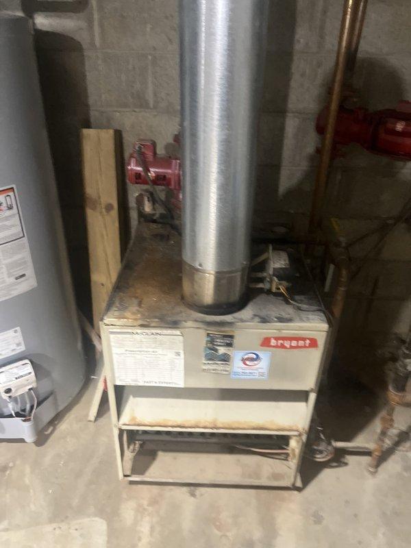 Conducted estimate for gas boiler replacement following flood damage to 35-year-old system that rendered unit inoperable. Assessed existing heating equipment, documented basement mechanical room conditions including furnace, water heater, and associated plumbing infrastructure with copper piping, brass fittings, and water treatment components visible throughout installation area.