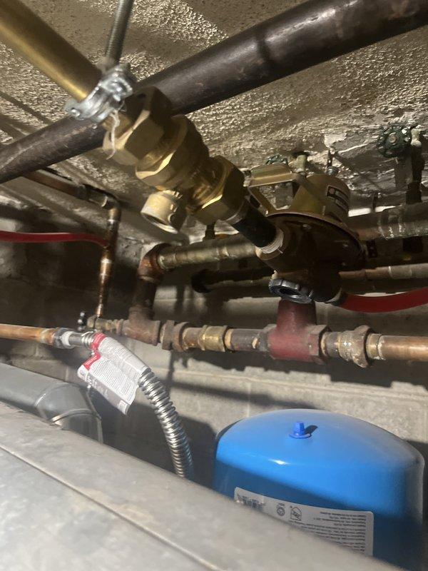 Conducted estimate for gas boiler replacement following flood damage to 35-year-old system that rendered unit inoperable. Assessed existing heating equipment, documented basement mechanical room conditions including furnace, water heater, and associated plumbing infrastructure with copper piping, brass fittings, and water treatment components visible throughout installation area.