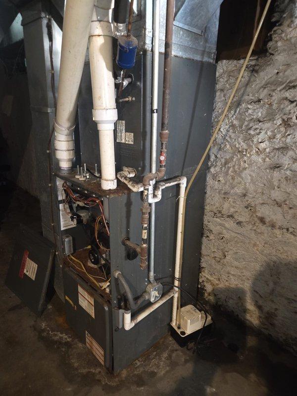 Completed HVAC system replacement estimate for rental property with existing basement upflow furnace installation. Assessed current system configuration including 90,000 BTU furnace with PVC venting, air conditioning condenser, refrigerant lines, and ductwork in concrete block basement utility area. Documented equipment specifications, measured existing duct dimensions (outdoor 3x18-250, 8x8-290), verified airflow requirements at 1,140 CFM, and noted current 16x25x1 filter size. Photographed complete system layout showing furnace unit, condensate drain lines, electrical connections, and associated HVAC components. Provided replacement options for both heating and cooling equipment to address customer's request for complete system upgrade.