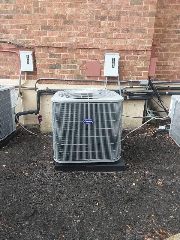 Completed commercial air conditioning system installation at multi-family residential property. Installed new Bryant 5-ton condensing unit on protective pad with proper clearances from building exterior, mounted on existing mulch bed against brick wall. Installed Bryant 5-ton cooling-only air handler in interior utility closet with all required electrical disconnects, control wiring, and safety labeling. Reused existing refrigerant line set and condensate drain piping, verifying integrity and proper insulation of all connections. Terminated all electrical connections to code specifications with appropriate disconnect switches mounted on exterior wall. System tested for proper operation, refrigerant charge verified, and airflow confirmed within manufacturer specifications. All work performed under permit and inspected per local building codes.