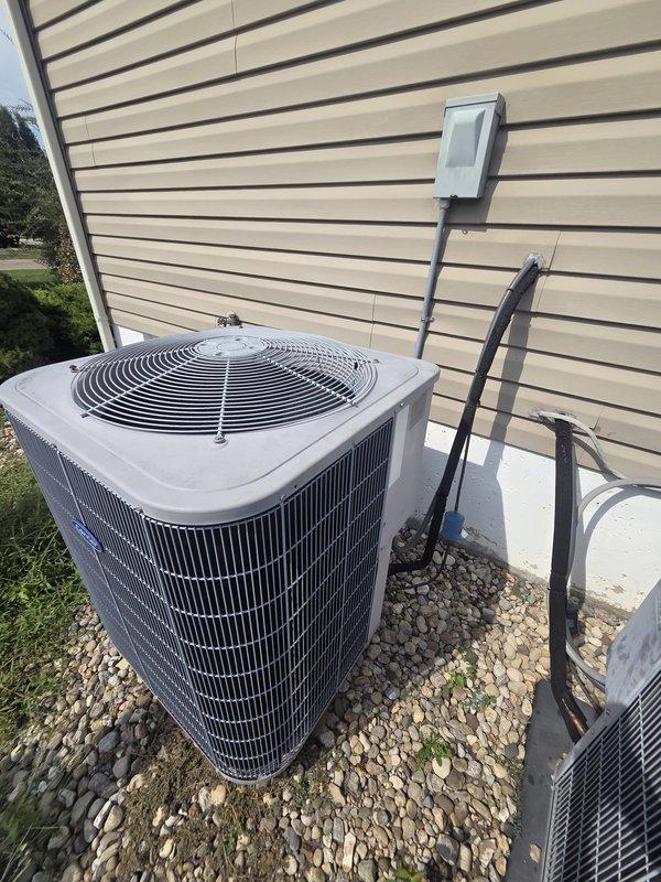 Conducted comprehensive assessment of existing residential HVAC system for replacement estimate. Evaluated outdoor air conditioning condenser unit positioned on gravel pad against home's exterior, noting current installation configuration with electrical conduit and weatherproof disconnect box. Inspected attic-mounted air handling unit and associated ductwork system, including black-wrapped supply ducts and flexible branch runs. Documented equipment specifications, installation conditions, and accessibility factors. Captured detailed photographic documentation of both outdoor condensing unit and indoor air handler locations to support equipment replacement proposal and ensure accurate system sizing recommendations.